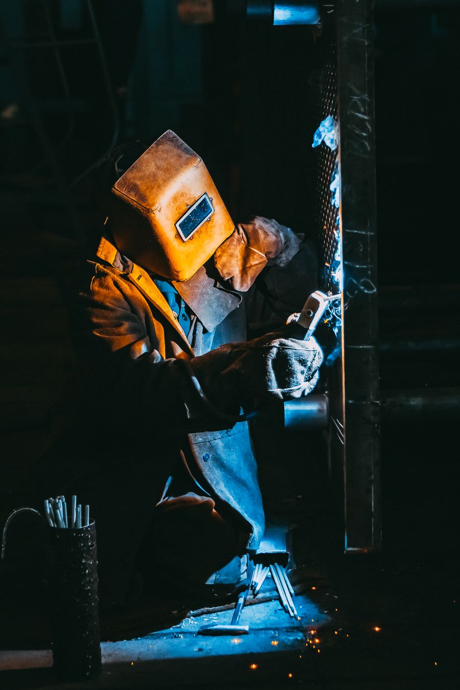 Soldador trabajando con chispas en un entorno industrial oscuro